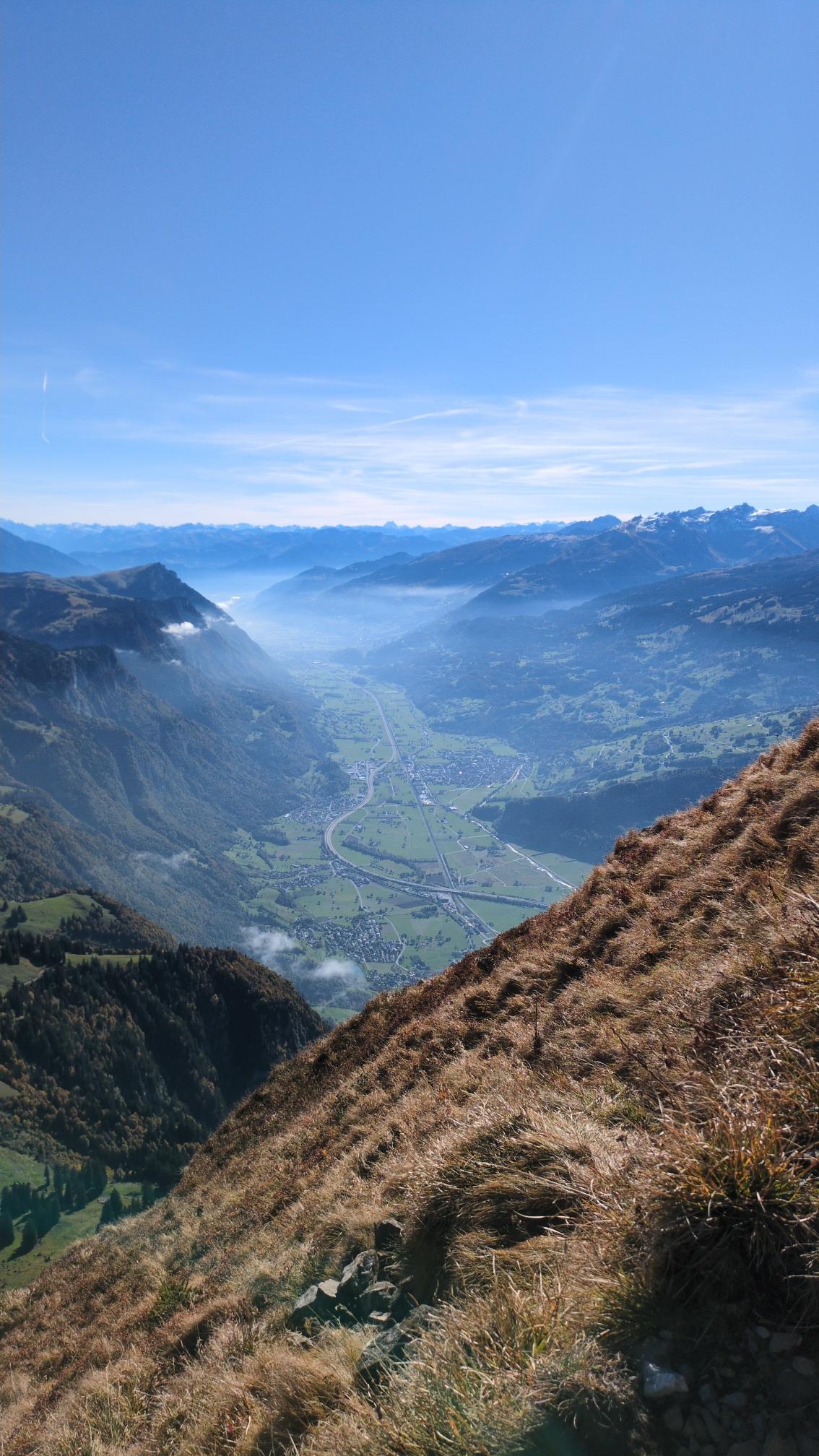 View from the summits towards south east. The high summits are snow covered. A thin layer of clouds moves from the Rhine valley towards Walensee. The valley is round about 1500m below us.