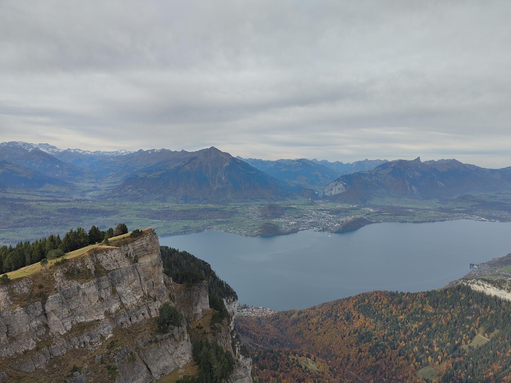 View from the summit over a lake and mountains. Very colourful trees in the valley