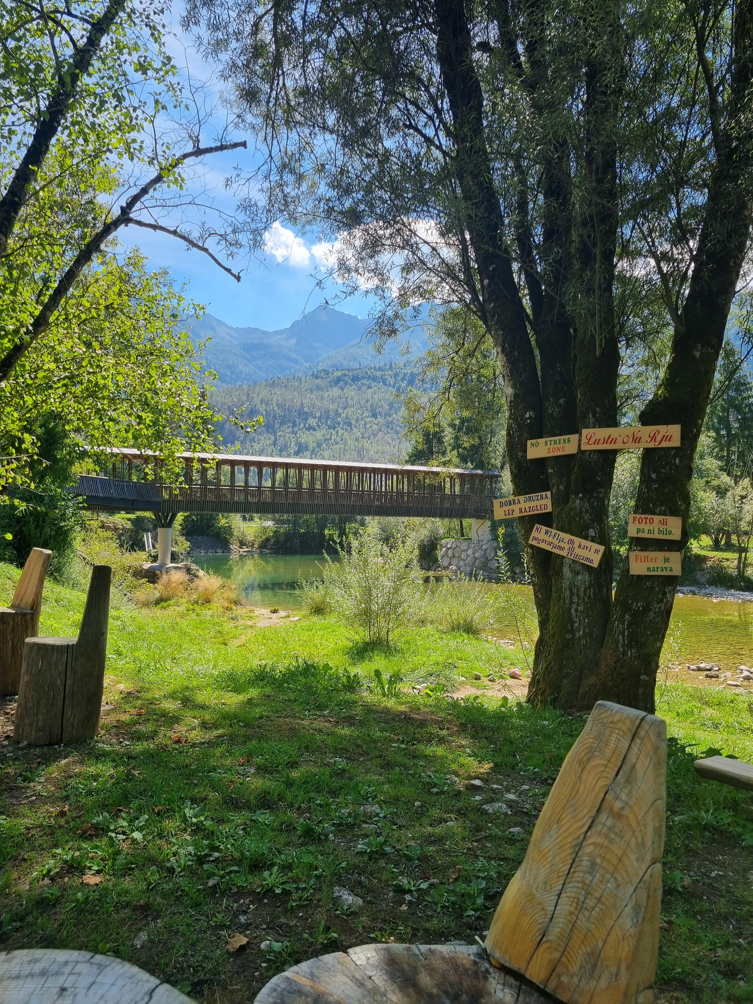 Resting area by the river with a bridge and mountains in the background