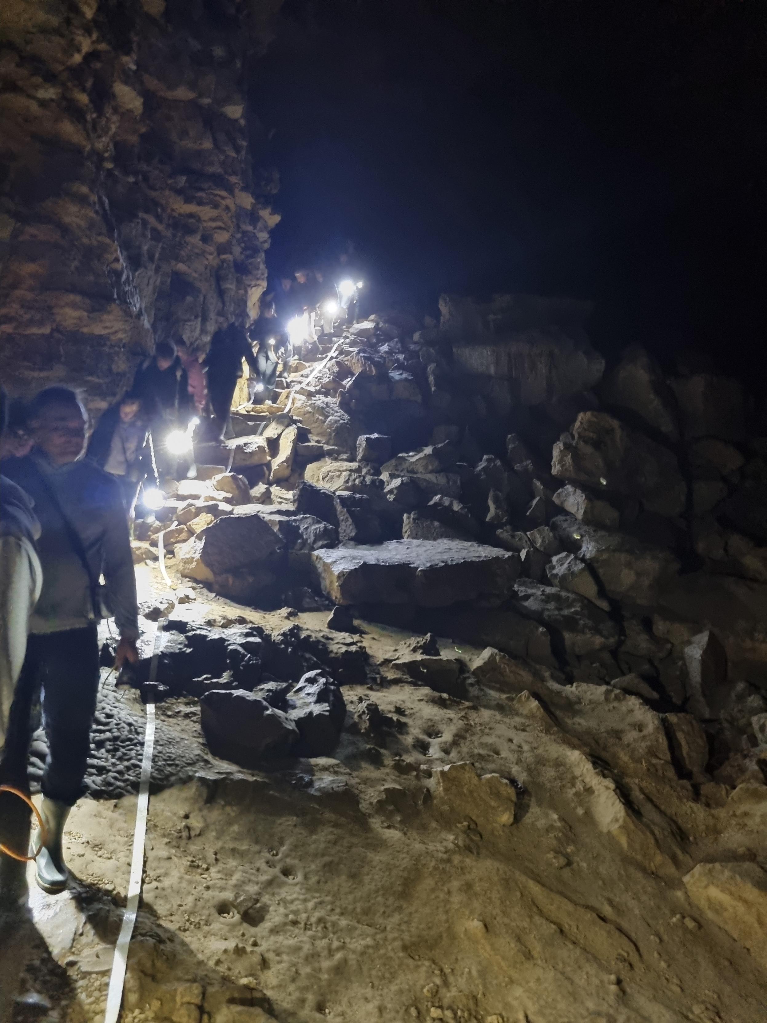 Group of visitors walking through a cave with torches
